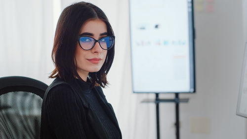 Portrait of young woman standing in office