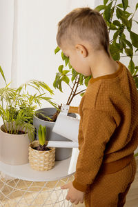 Adorable, cute boy caring of indoor plants at home. a little helper in the household
