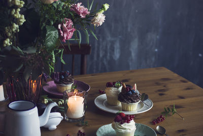 Flower vase and cup cakes in plates on table