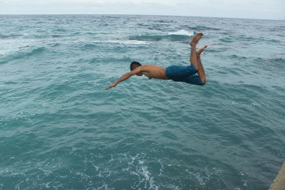 Man swimming in sea against sky