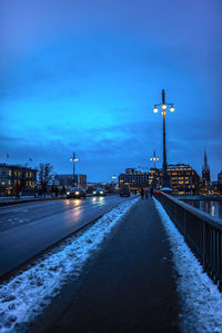 Illuminated city street against blue sky