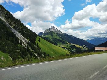 Road by mountains against sky