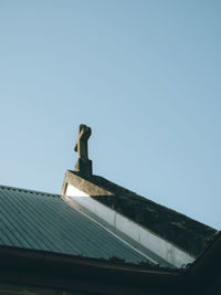 Low angle view of cross on roof against sky