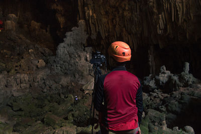 Rear view of man photographing in cave
