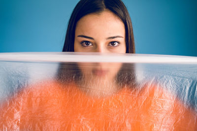 Close-up portrait of a beautiful young woman over blue background