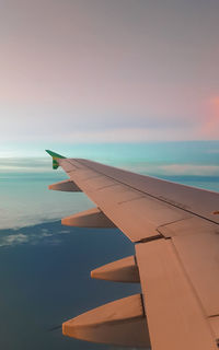 Airplane flying over sea against sky during sunset