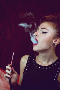 Close-up of young woman smoking hookah