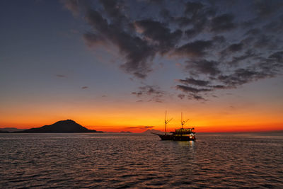 Silhouette sailboat in sea against sky during sunset