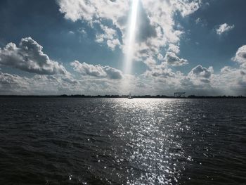 Scenic view of sea against cloudy sky on sunny day