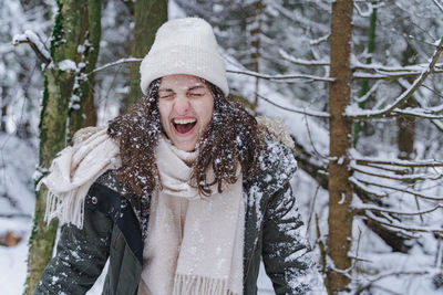 Portrait of woman standing by tree during winter