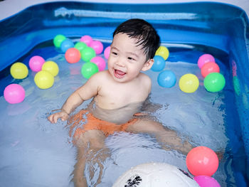 Full length of happy boy with toy in swimming pool