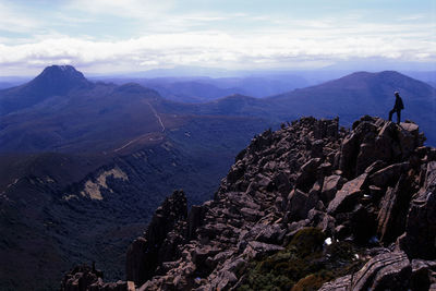 Man on rocky mountain against sky