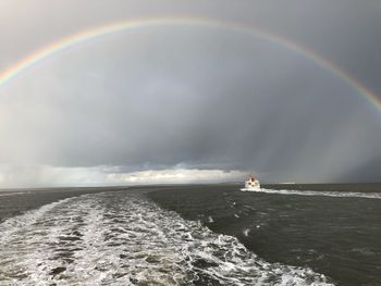 Scenic view of rainbow over sea against sky