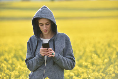 Young woman using phone on field