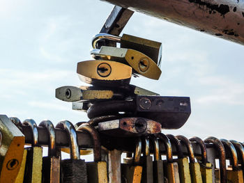 Close-up of padlocks hanging on metal against sky