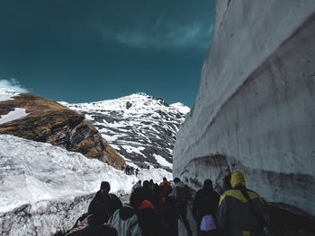 People on snowcapped mountain against sky