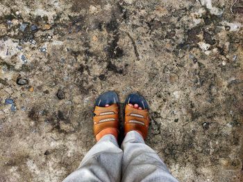 Two men's feet wearing sandals, on an uneven floor.