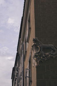 Low angle view of statue by building against sky