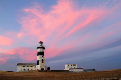 Lighthouse by sea against sky