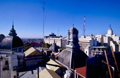 Buildings in city against clear blue sky