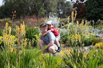 Happy grandfather and grandson playing amidst flowering plants at park