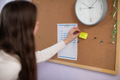 A teenager tapes a piece of paper to the board with a word written in english.