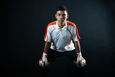 Portrait of young man standing against black background