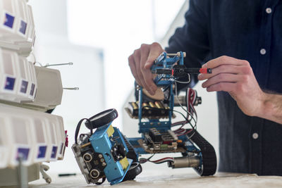 Midsection of engineer making drone in office