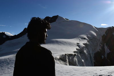 Rear view of man standing on snow covered mountain