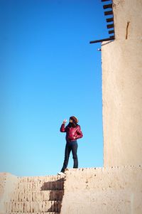 Man with umbrella against blue sky