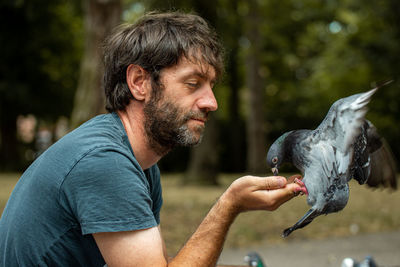 Side view of man feeding bird