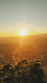 Sunlight streaming on landscape against sky during sunset