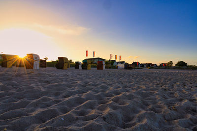 Scenic view of beach by buildings against sky during sunset