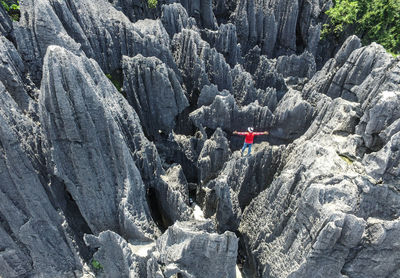 High angle view of mid adult man with arms outstretched standing on rocky mountains