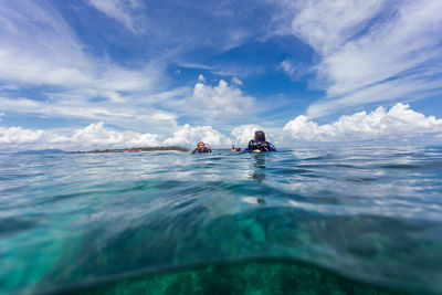 People swimming in sea against sky