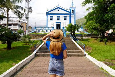 Tourist girl in front of the church igreja matriz in the historic center of ilhabela island, brazil.