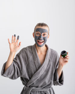 Womens health. spa and wellness. happy woman applying face mask waving hello