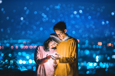 Couple holding illuminated string light at night