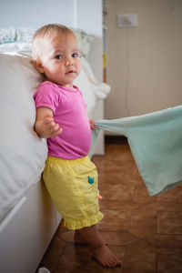 High angle view of cute baby girl sitting on bed at home