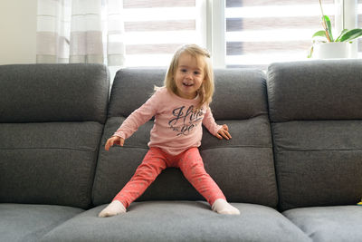 2 year old baby girl on couch in bright interior. active child concept