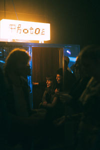 Happy transgender woman with non-binary gender illuminated photo booth in club