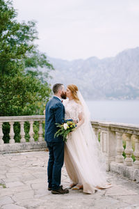 Rear view of couple holding hands against clear sky