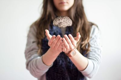 Close-up of woman holding hair over white background