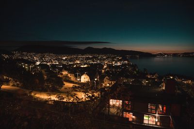 High angle view of illuminated town by sea against sky