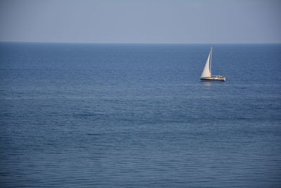 Sailboat sailing on sea against clear sky