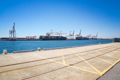 Commercial dock by sea against clear sky