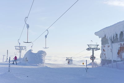 Ski lift over snowcapped mountains against sky