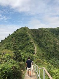 Rear view of man walking on mountain against sky