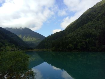 Scenic view of lake and mountains against cloudy sky at jiuzhaigou