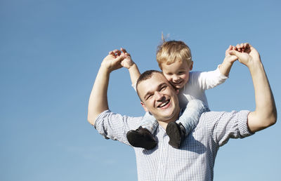 Cheerful father and son against sky